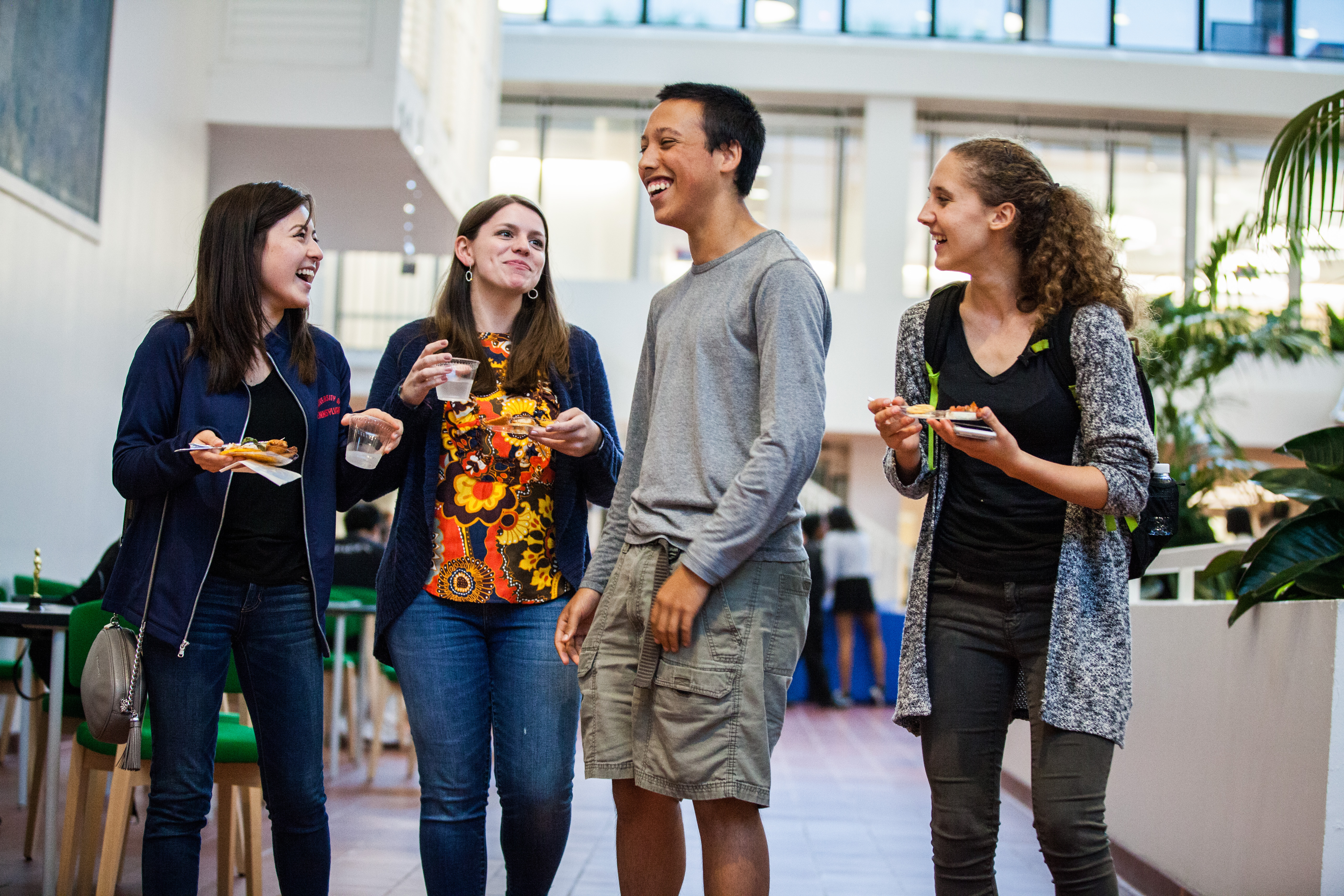Four students laughing together in the Hill College House atrium
